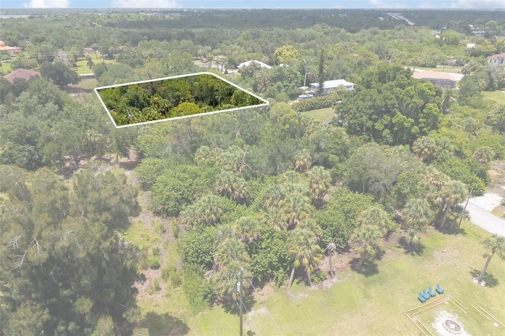 An aerial view shows a wooded lot highlighted by a white outline in a neighborhood — 186 NORTHSHORE TERRACE, PUNTA GORDA, FL