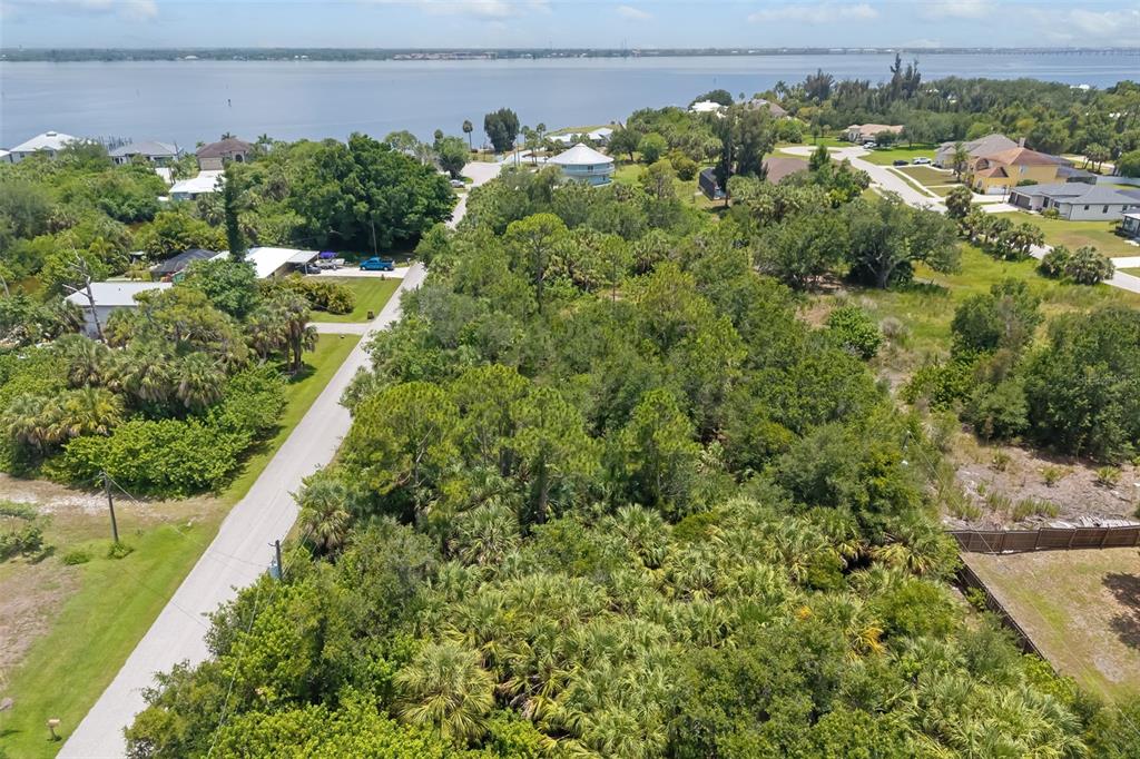 An aerial view shows a wooded lot adjacent to a road near a large body of water — 186 NORTHSHORE TERRACE, PUNTA GORDA, FL