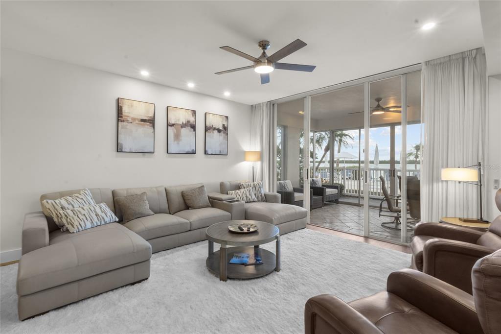A living room features a large sectional sofa, a coffee table, and sliding glass doors — 615 DREAM ISLAND PLACE UNIT 105, LONGBOAT KEY, FL