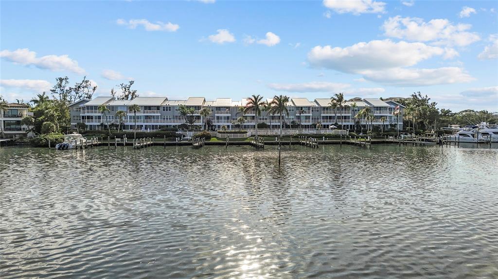 A multi-story waterfront apartment building features balconies and a private boat dock — 615 DREAM ISLAND PLACE UNIT 105, LONGBOAT KEY, FL