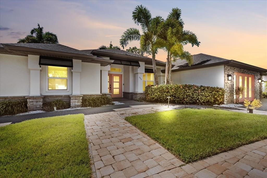 A single-story house with a stone facade, palm trees, and a paved walkway at dusk — 2415 W PRICE BOULEVARD, NORTH PORT, FL