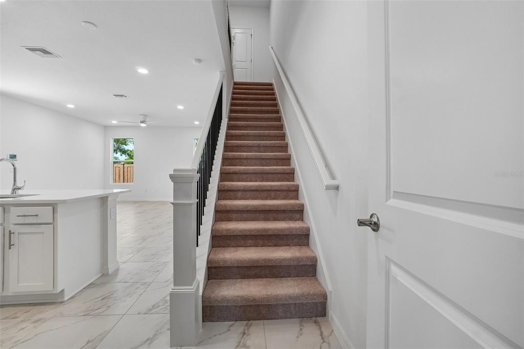 A carpeted staircase with a black metal railing leads to an upper floor in a home — 610 SILVER STREAM COURT, BRANDON, FL