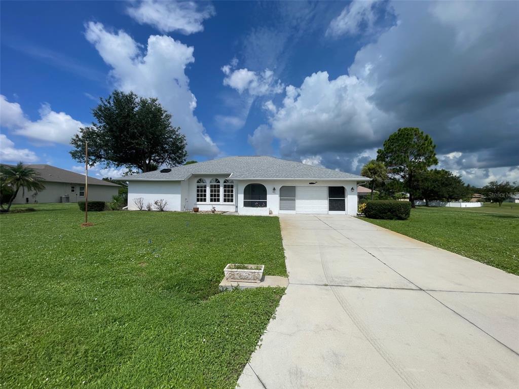 A single-story white house with a gray roof and a concrete driveway under a cloudy sky — 1091 VENTURE COURT, PUNTA GORDA, FL