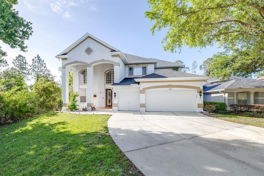 A two-story house with a white stucco facade, a two-car garage, and a concrete driveway — 10102 DEERCLIFF DRIVE, TAMPA, FL