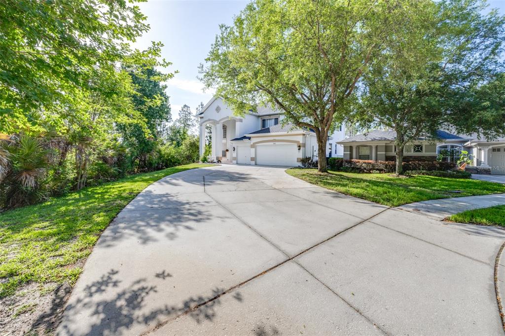 A two-story house with a white exterior, a three-car garage, and a large concrete driveway — 10102 DEERCLIFF DRIVE, TAMPA, FL