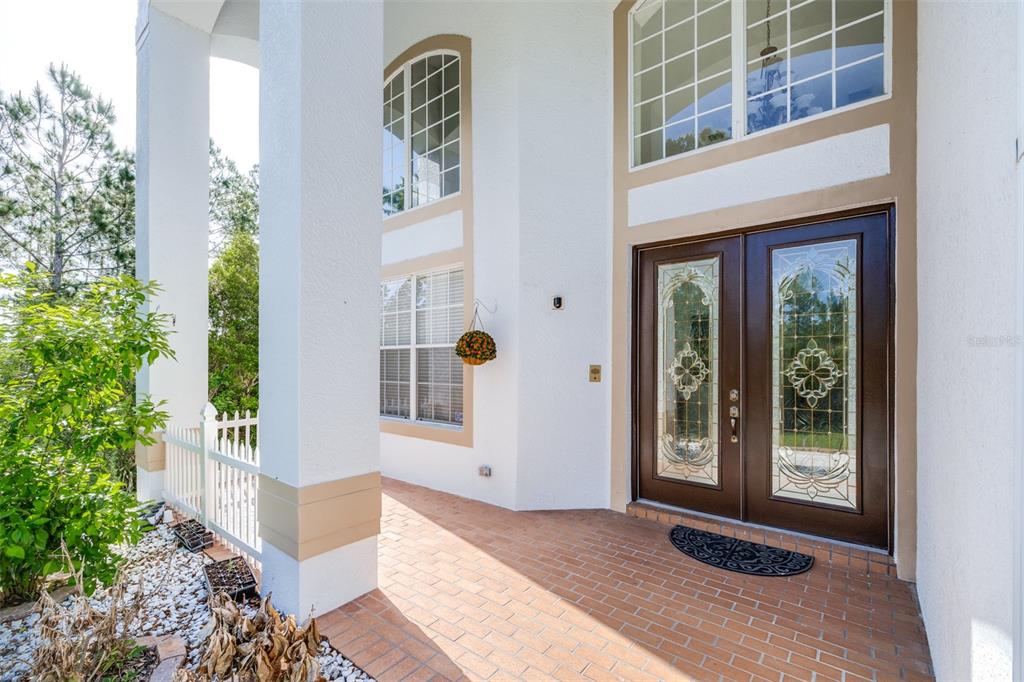 A brick porch leads to a double front door with decorative glass inserts — 10102 DEERCLIFF DRIVE, TAMPA, FL
