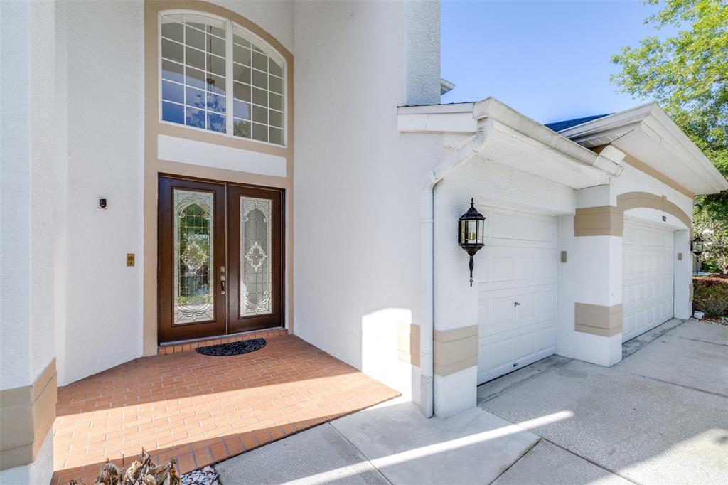 The exterior of a house features a brick porch, double front doors, and a garage — 10102 DEERCLIFF DRIVE, TAMPA, FL