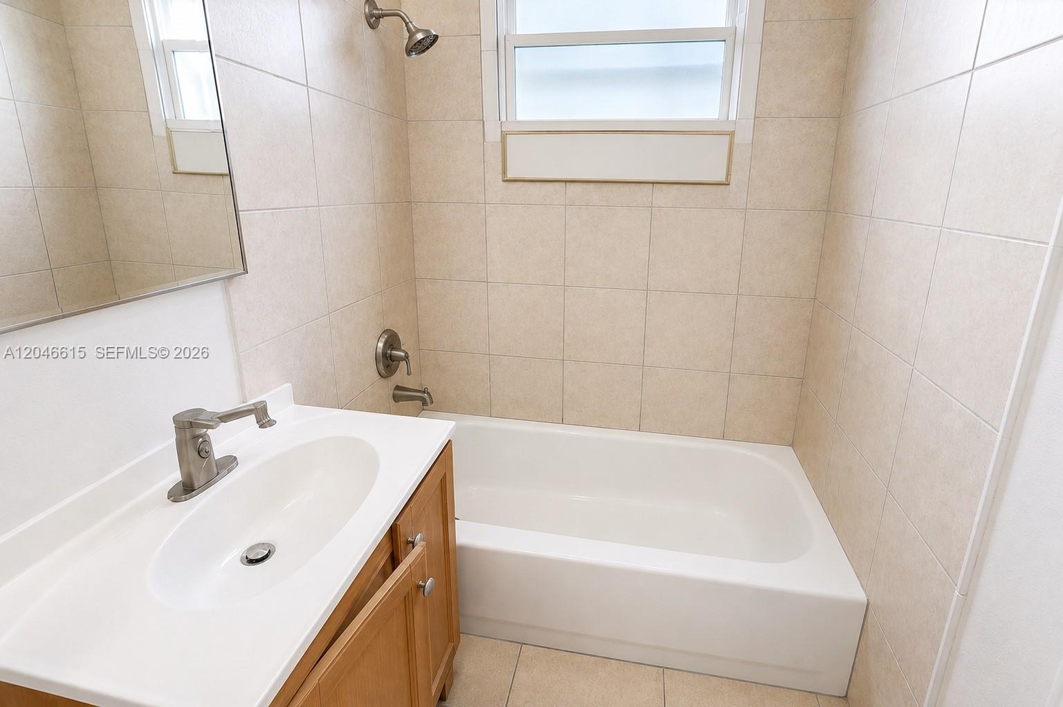 A bathroom features a white bathtub, a tiled shower surround, and a wooden vanity cabinet — 1211 Kasim St, Opa-Locka FL 33054, OPA-LOCKA, FL