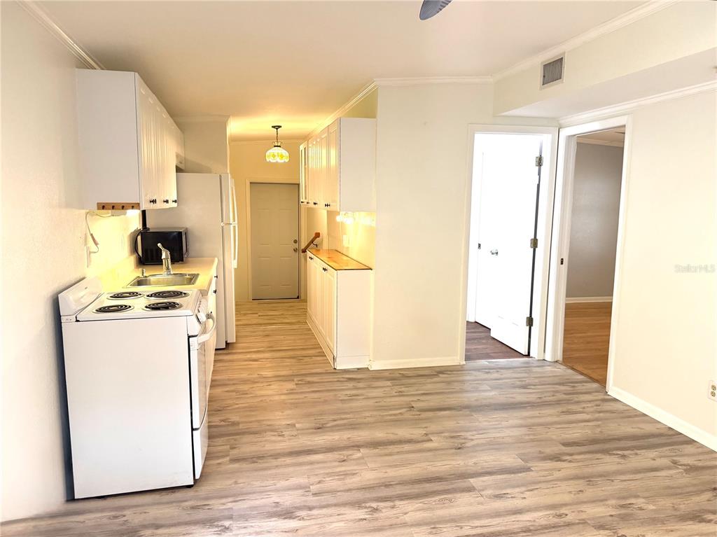 A kitchen features white cabinets, a white stove, wood-look flooring, and an adjacent doorway — 516 NORTHMOOR AVENUE N, ST PETERSBURG, FL