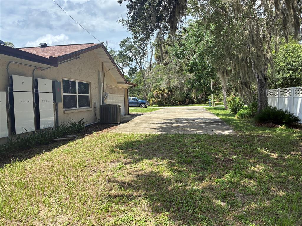 The exterior side of a house features two Tesla Powerwalls and a concrete driveway — 6383 N JADE TERRACE, CRYSTAL RIVER, FL