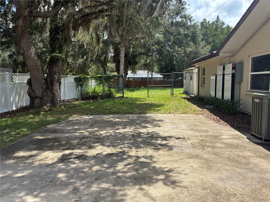 A concrete driveway leads to a backyard with a chain-link fence and Tesla Powerwalls — 6383 N JADE TERRACE, CRYSTAL RIVER, FL