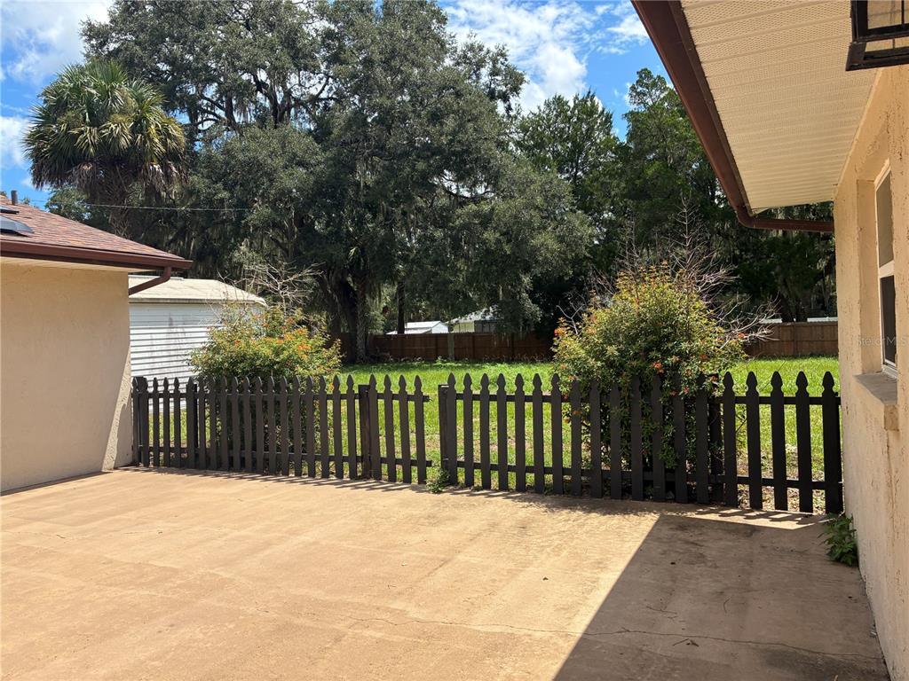 A concrete patio overlooks a fenced backyard with mature trees and a small shed — 6383 N JADE TERRACE, CRYSTAL RIVER, FL