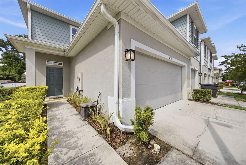 A two-story townhouse exterior features a gray garage, a front door, and a concrete walkway — 2130 LACEFLOWER DRIVE, BRANDON, FL