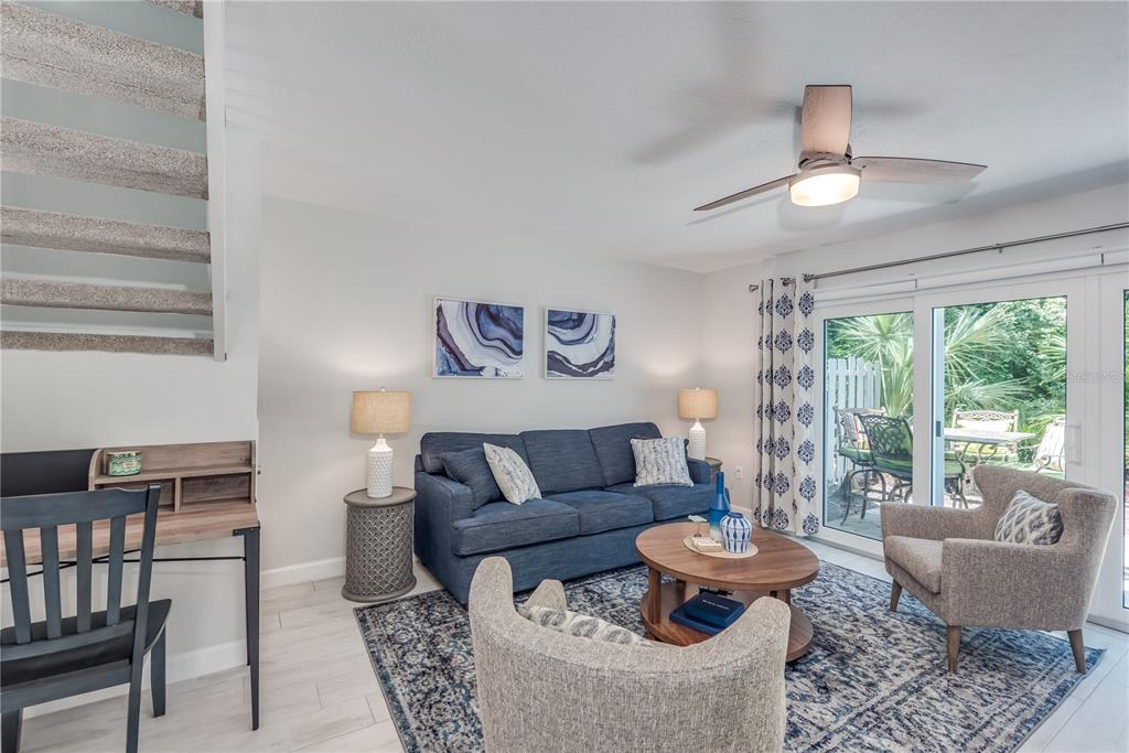 A living room features a blue sofa, two armchairs, a desk, and sliding glass doors — 218 SEAPORT BOULEVARD UNIT T48, CAPE CANAVERAL, FL