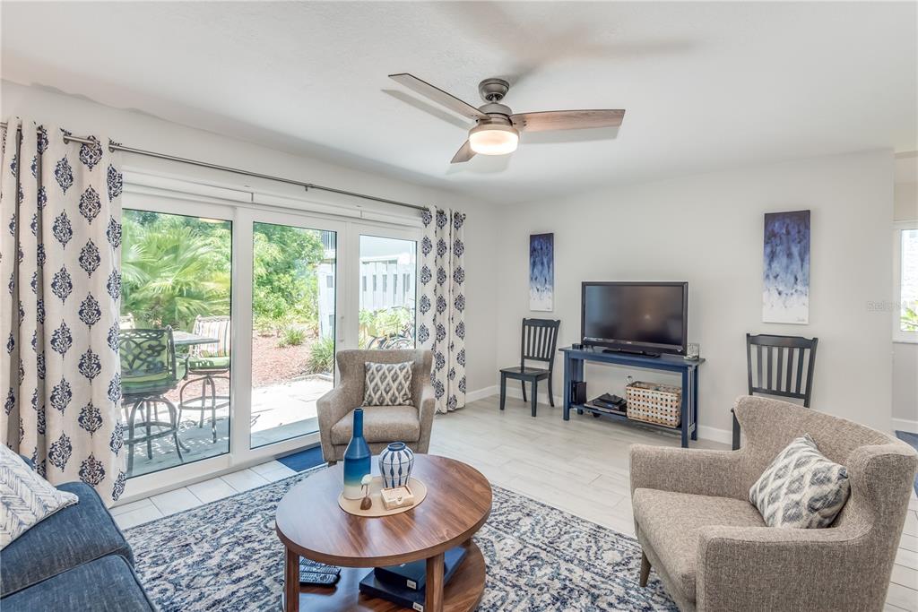 A living room features a ceiling fan, patterned curtains, two armchairs, and a sliding glass door — 218 SEAPORT BOULEVARD UNIT T48, CAPE CANAVERAL, FL