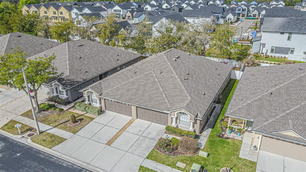 An aerial view shows a suburban neighborhood with several single-story homes featuring gray shingled roofs — 1123 BENSBROOKE DRIVE, WESLEY CHAPEL, FL