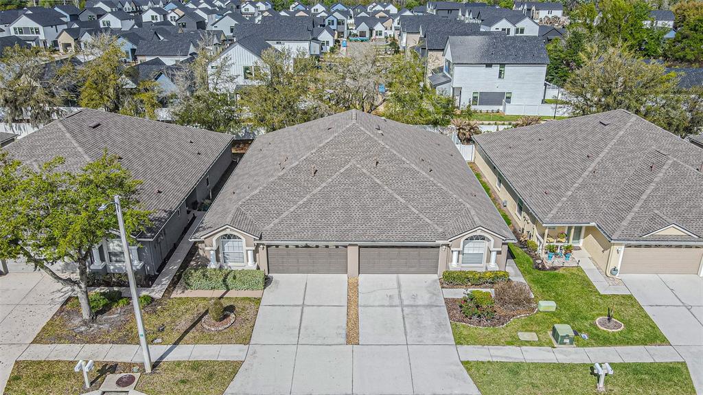 An aerial view shows a duplex home with two garages and a shared driveway — 1123 BENSBROOKE DRIVE, WESLEY CHAPEL, FL