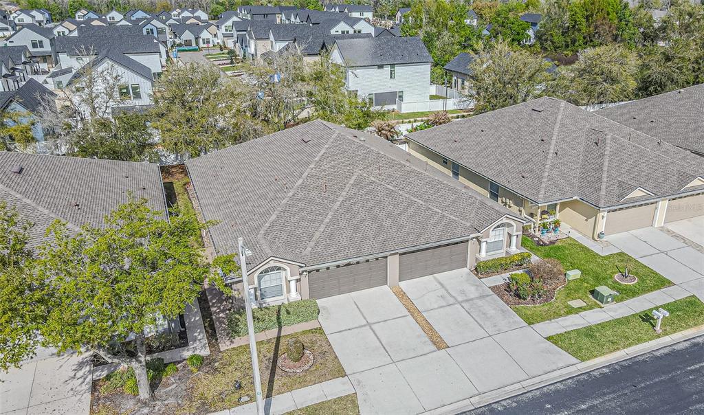 An aerial view of a suburban duplex with gray shingled roofs and concrete driveways — 1123 BENSBROOKE DRIVE, WESLEY CHAPEL, FL
