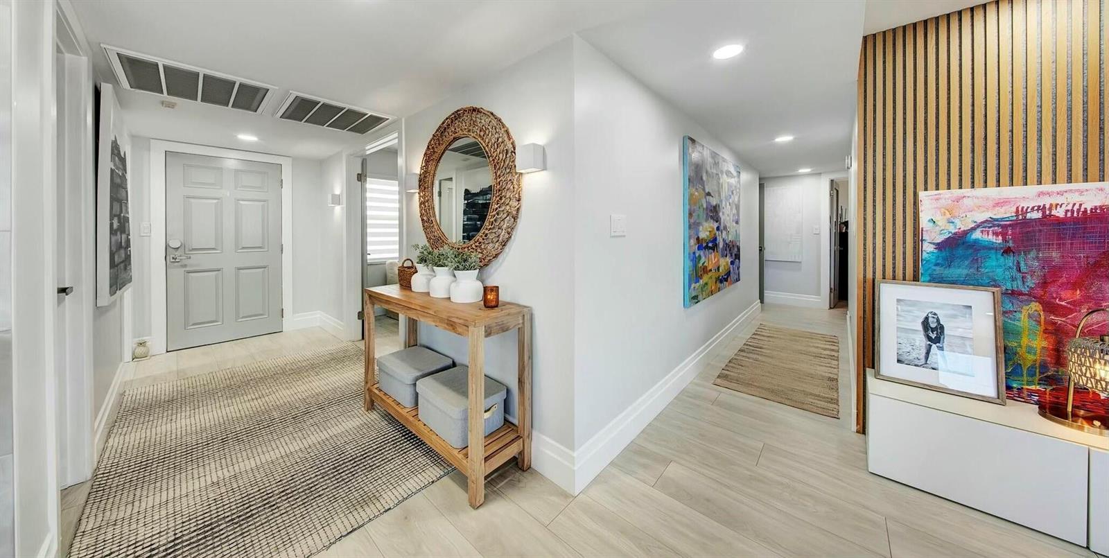A bright entryway features light wood flooring, a wooden console table, and colorful wall art — 2871 N Ocean Boulevard N # D502, Boca Raton FL 33431, BOCA RATON, FL