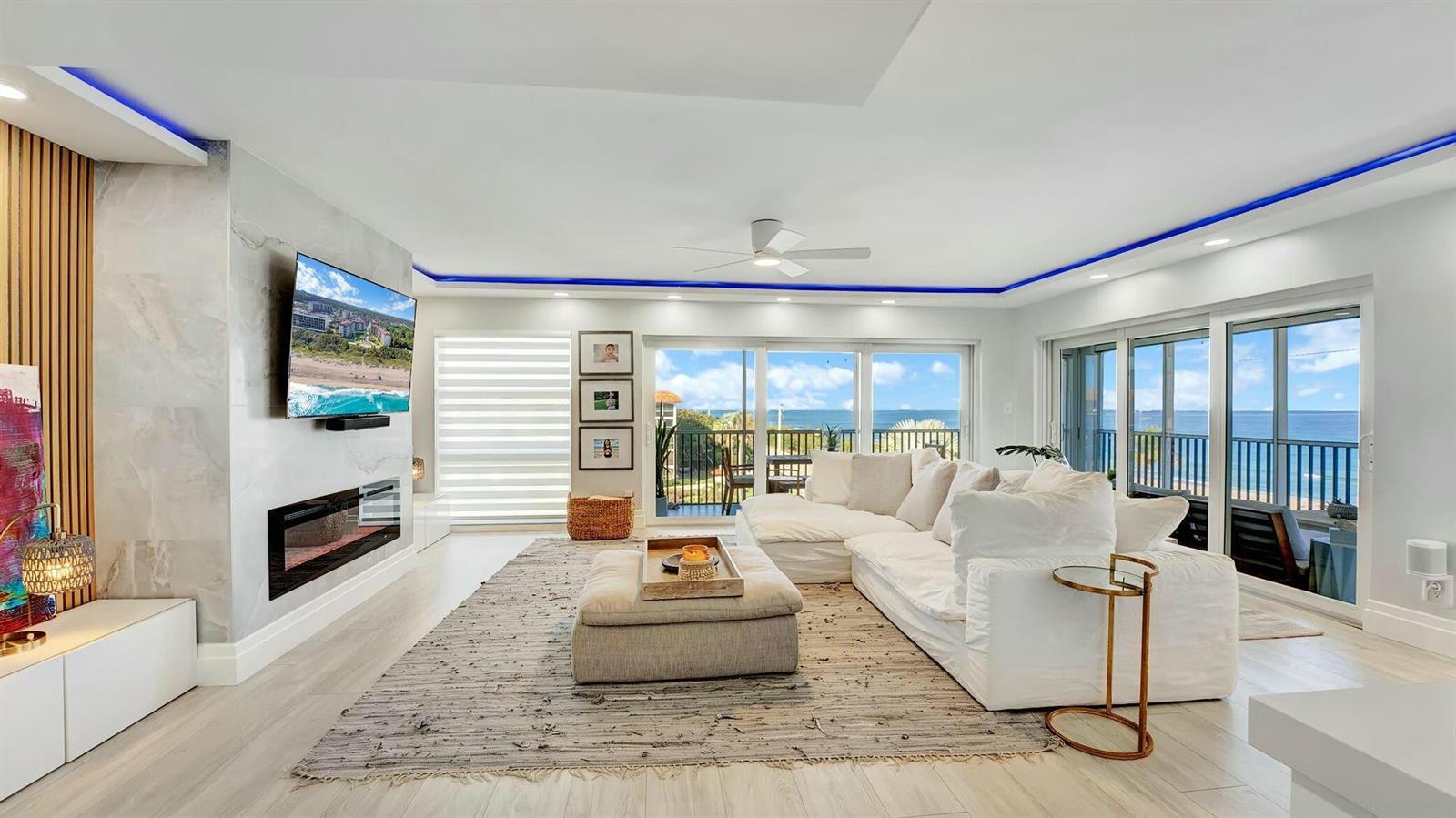 A bright living room features a white sectional sofa, fireplace, and sliding doors overlooking the ocean — 2871 N Ocean Boulevard N # D502, Boca Raton FL 33431, BOCA RATON, FL