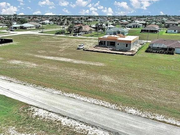 An aerial view shows a large vacant lot with a house under construction — 1037 NW 37TH PLACE, CAPE CORAL, FL