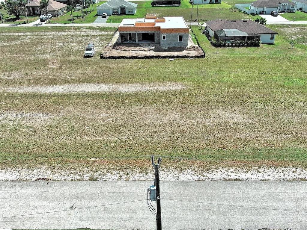 An aerial view shows a house under construction on a large, grassy residential lot — 1037 NW 37TH PLACE, CAPE CORAL, FL