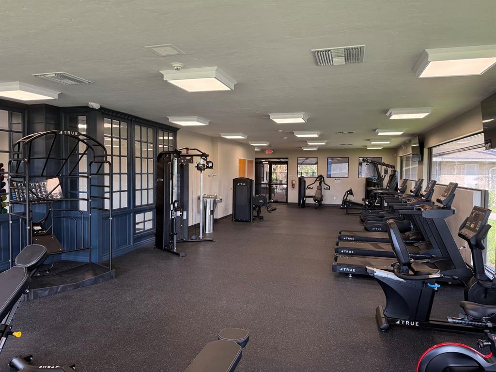This gym features black-framed windows, rubber flooring, and a row of True brand exercise equipment — 2230 NW 23RD LOOP, OCALA, FL