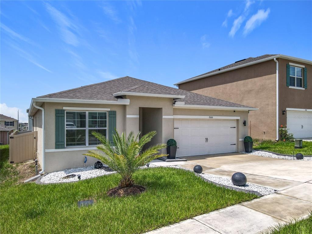 A single-story house with a beige stucco exterior, a two-car garage, and green shutters — 2000 CHICKASAW BOULEVARD, DAVENPORT, FL