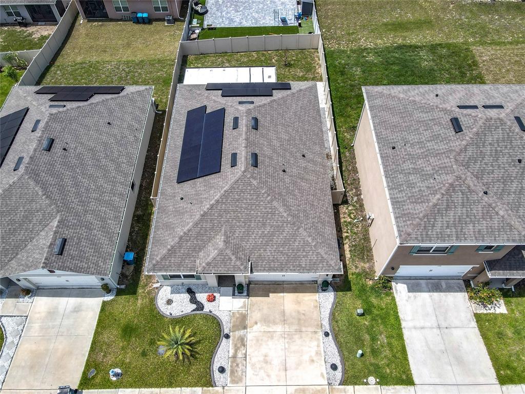 An aerial view shows three suburban houses with shingled roofs and solar panels — 2000 CHICKASAW BOULEVARD, DAVENPORT, FL