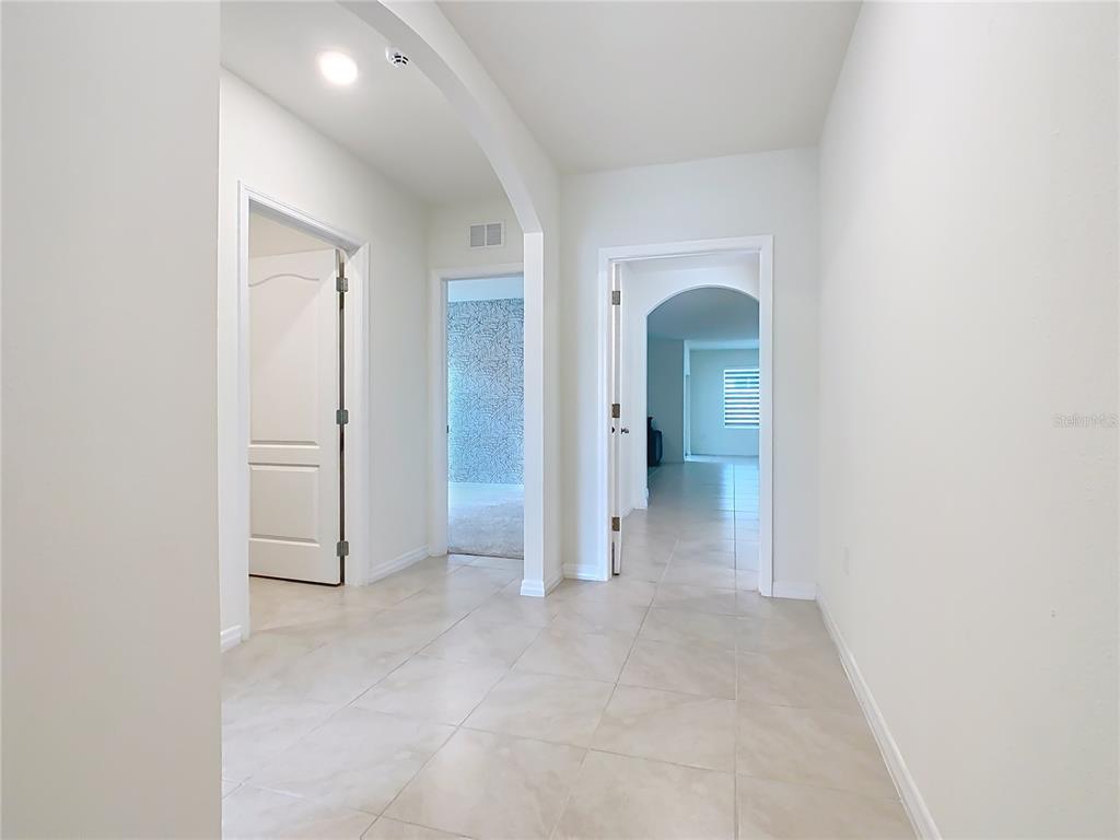 A hallway with light tile flooring leads to multiple doorways and an arched entryway — 2000 CHICKASAW BOULEVARD, DAVENPORT, FL
