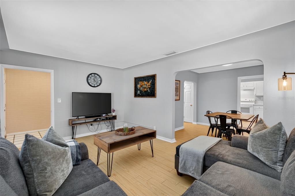 A living room with gray walls, light wood flooring, a television, and a sectional sofa — 2401 19TH STREET S, ST PETERSBURG, FL