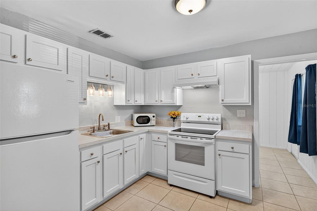 A kitchen features white cabinets, a white refrigerator, a white stove, and tile flooring — 2401 19TH STREET S, ST PETERSBURG, FL