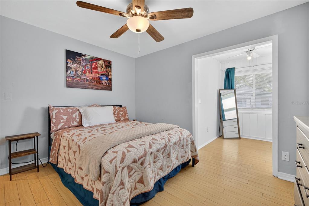 A bedroom with light wood flooring, a ceiling fan, and a bed with patterned bedding — 2401 19TH STREET S, ST PETERSBURG, FL