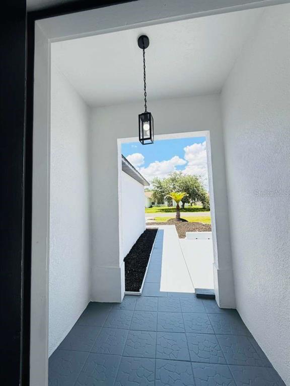 A covered entryway features a gray tiled floor, a hanging lantern, and a view outside — 665 REGENCY WAY, KISSIMMEE, FL