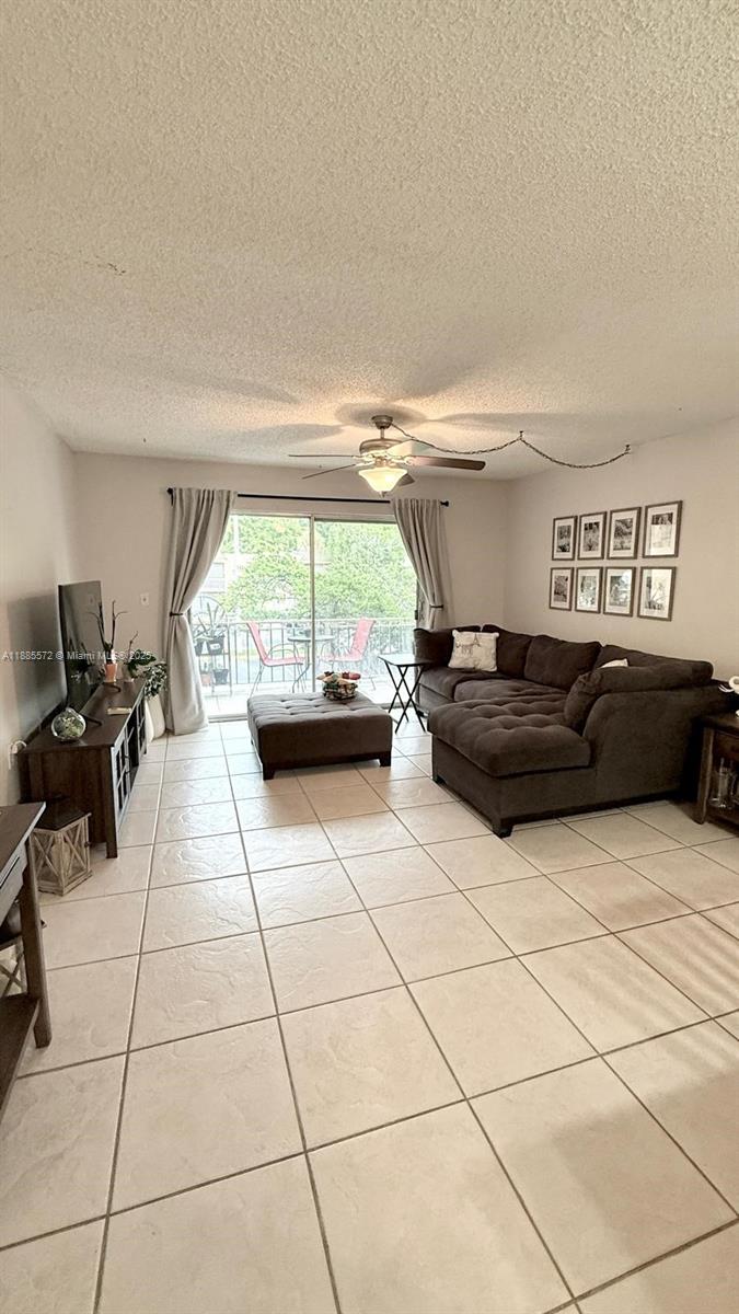 A living room features a brown sectional sofa, tile flooring, and a sliding glass door — 13700 SW 62nd St # 250, Miami FL 33183, MIAMI, FL