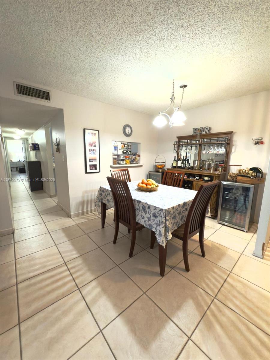 A dining room features a table with chairs, a bar cabinet, and tile flooring — 13700 SW 62nd St # 250, Miami FL 33183, MIAMI, FL