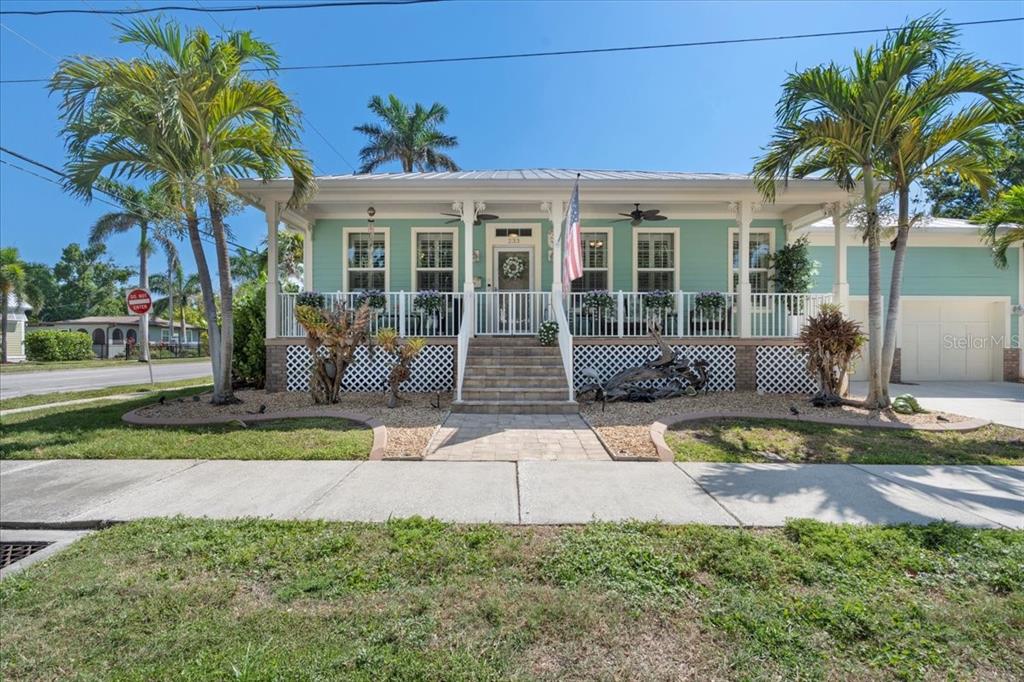 A light green, single-story house with a front porch, lattice skirting, and two palm trees — 233 DURRANCE STREET, PUNTA GORDA, FL