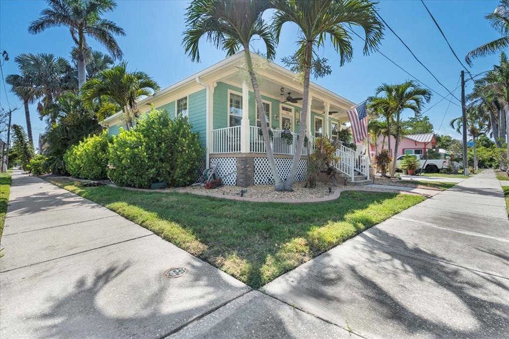 A light green house with a front porch, white railings, and palm trees in the yard — 233 DURRANCE STREET, PUNTA GORDA, FL