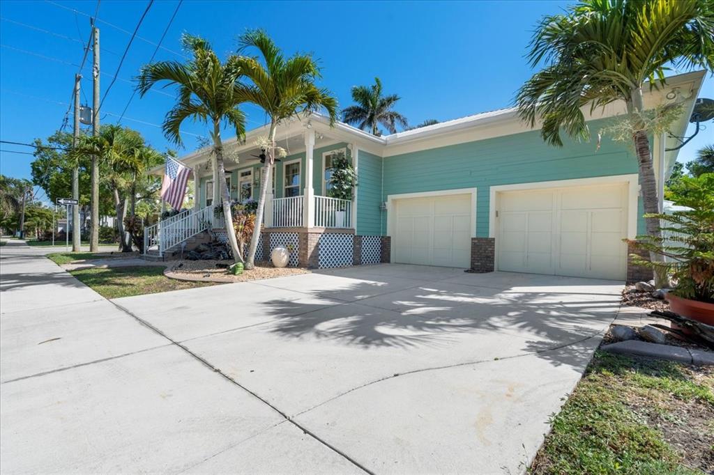 A teal house with a front porch and palm trees sits on a corner lot — 233 DURRANCE STREET, PUNTA GORDA, FL