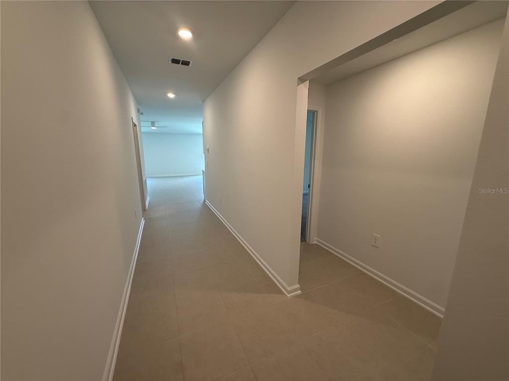 A long, tiled hallway with light-colored walls leads toward an open living area — 3228 ALPINE WAY, DAVENPORT, FL