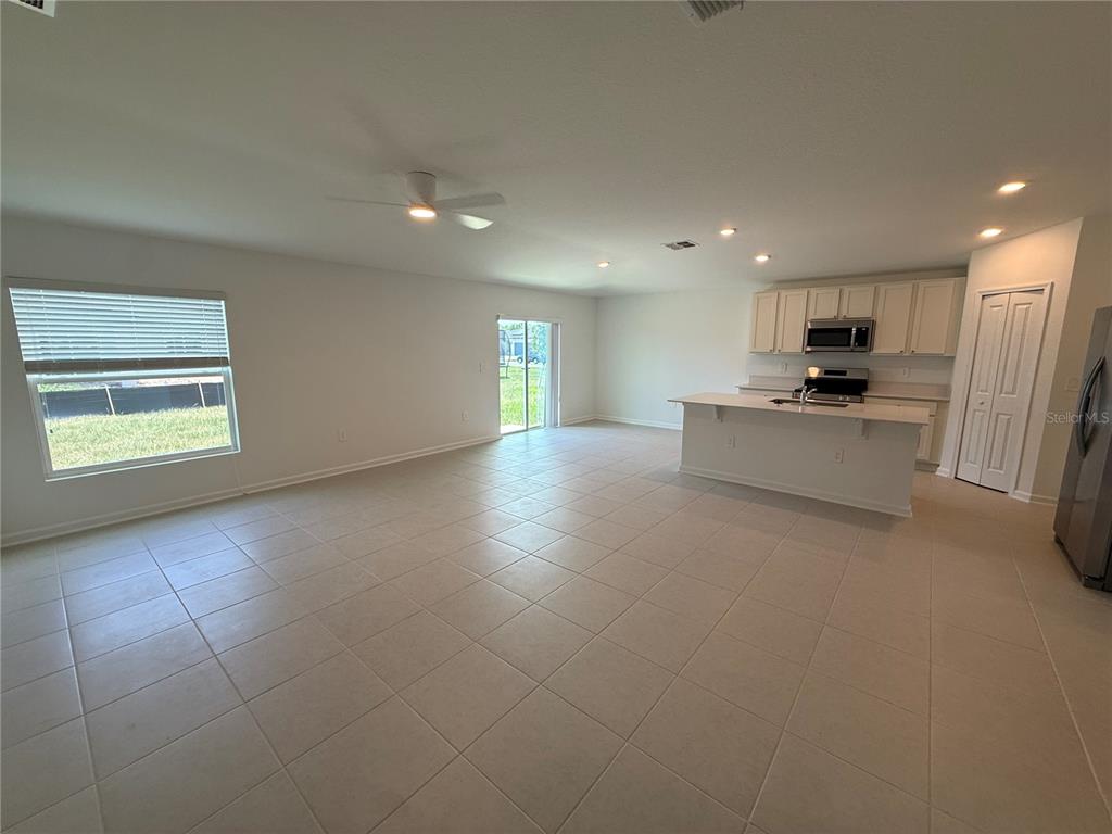 An open-concept living area features light tile flooring, a kitchen island, and white cabinetry — 3228 ALPINE WAY, DAVENPORT, FL