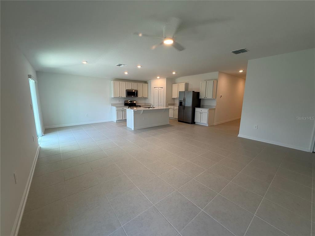 An open-concept kitchen and living area features white cabinetry, a center island, and tile flooring — 3228 ALPINE WAY, DAVENPORT, FL