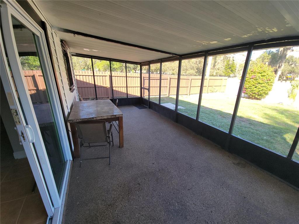 A screened-in porch features a tile-topped table, concrete flooring, and views of a fenced yard — 11102 MAHIN LANE, RIVERVIEW, FL