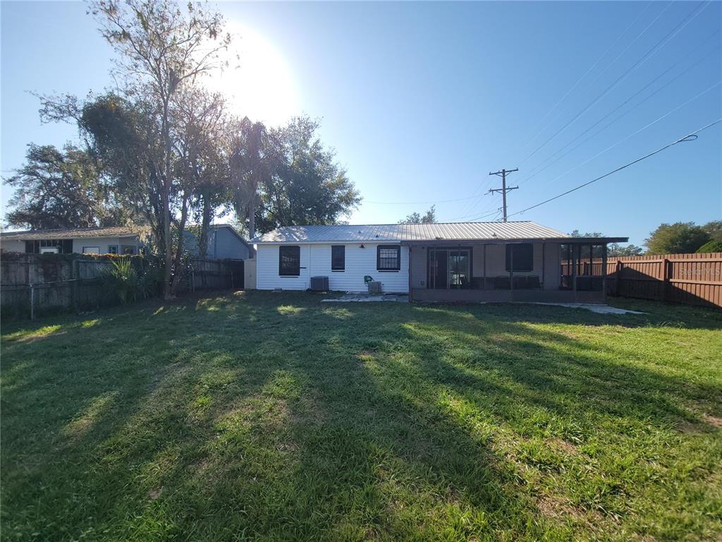 A white house with a metal roof and a screened-in porch sits in a backyard — 11102 MAHIN LANE, RIVERVIEW, FL
