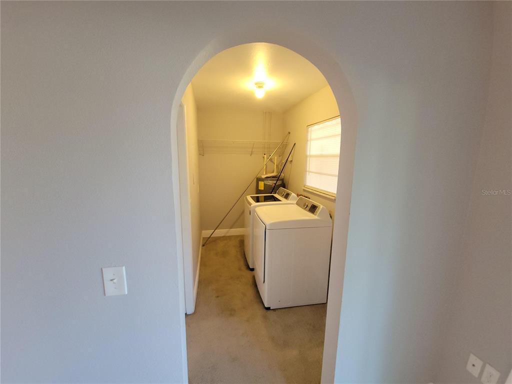 A laundry room with a washer and dryer sits behind an arched doorway — 11102 MAHIN LANE, RIVERVIEW, FL