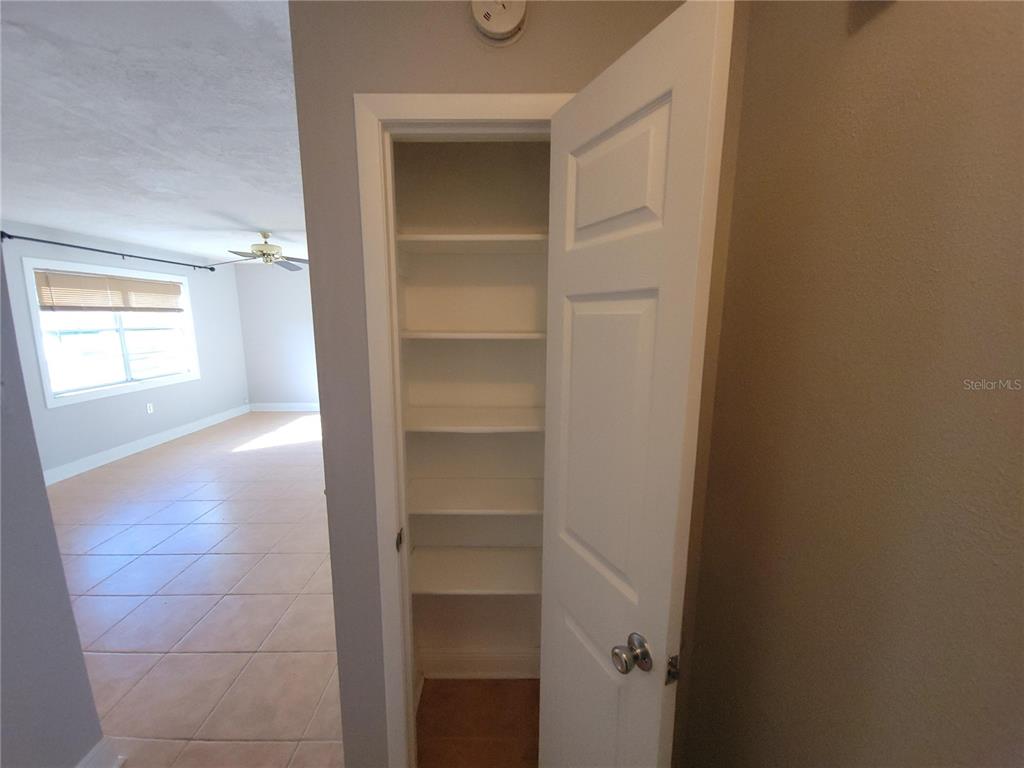 An open white door reveals a narrow closet with multiple shelves inside a tiled room — 11102 MAHIN LANE, RIVERVIEW, FL