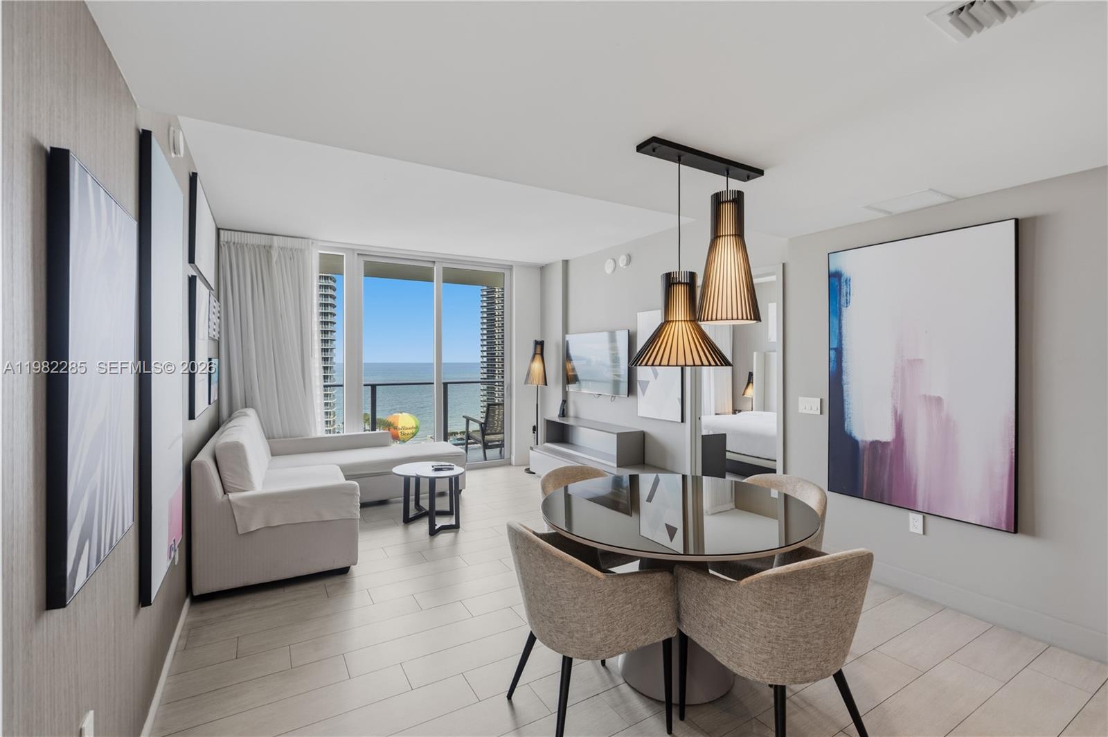 A modern living and dining area features a glass table, sectional sofa, and ocean view — 4010 S Ocean Dr # R2005, Hollywood FL 33019, HOLLYWOOD, FL