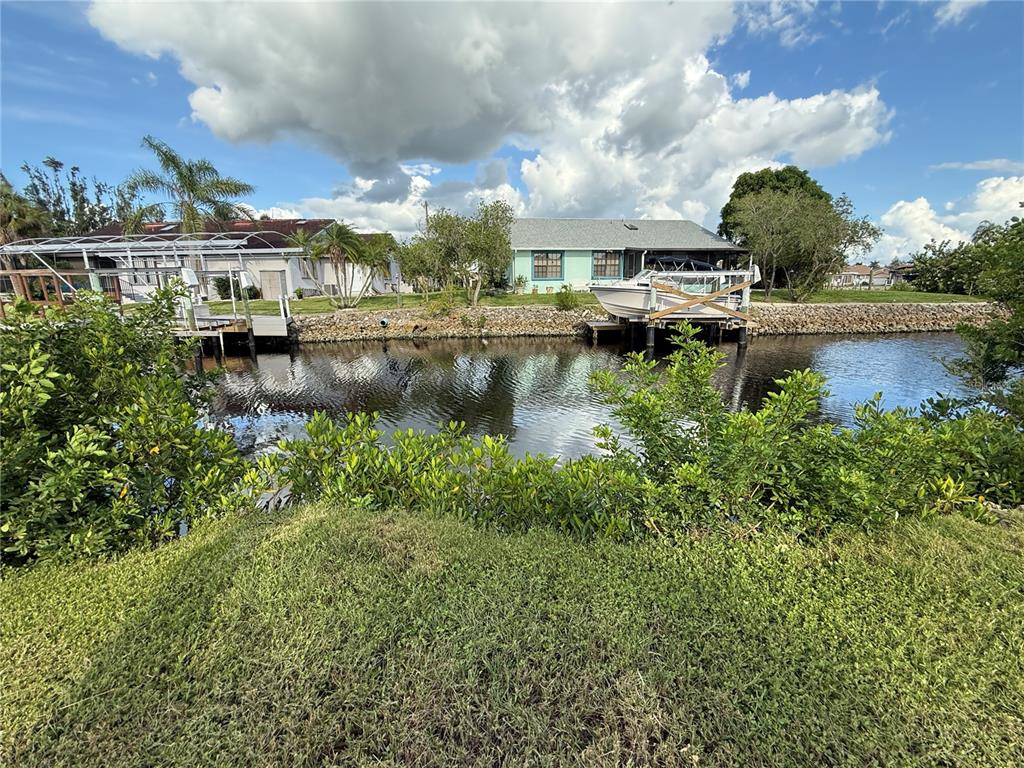 A canal-front view shows two houses, a boat lift, and a dock with lush vegetation — 3800 BAYNARD DRIVE, PUNTA GORDA, FL