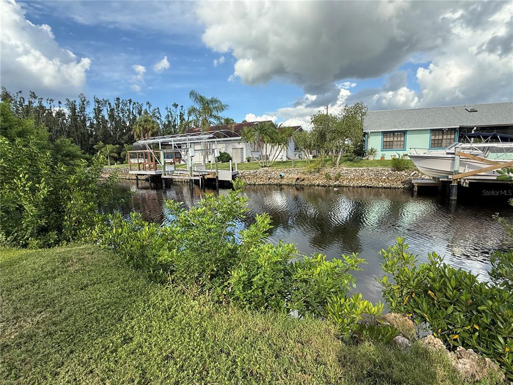A canal view showing two houses with private boat docks and lush vegetation — 3800 BAYNARD DRIVE, PUNTA GORDA, FL
