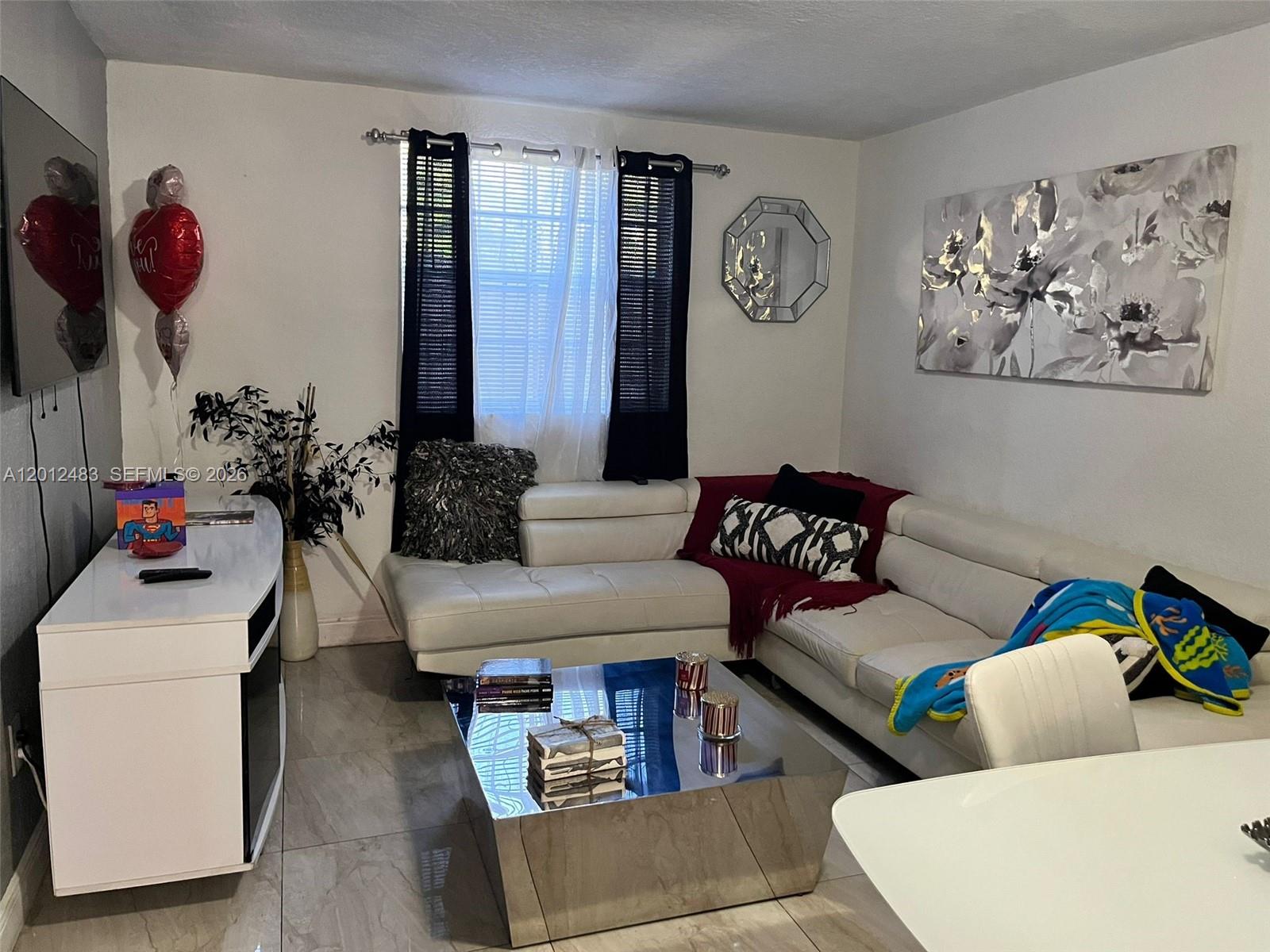 A living room features a white sectional sofa, a mirrored coffee table, and tile flooring — 652 NW 3rd St # 103, Miami FL 33128, MIAMI, FL
